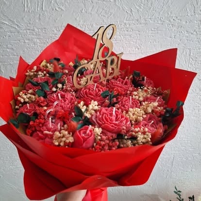Red wrapped flower bouquet with pink carnations, white babys breath, and dried flowers, topped with a golden Love 18 ornament