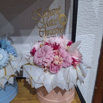 Pink and white tiered cake decorated with fresh flowers and a gold script topper reading Kodman Maia Treasure